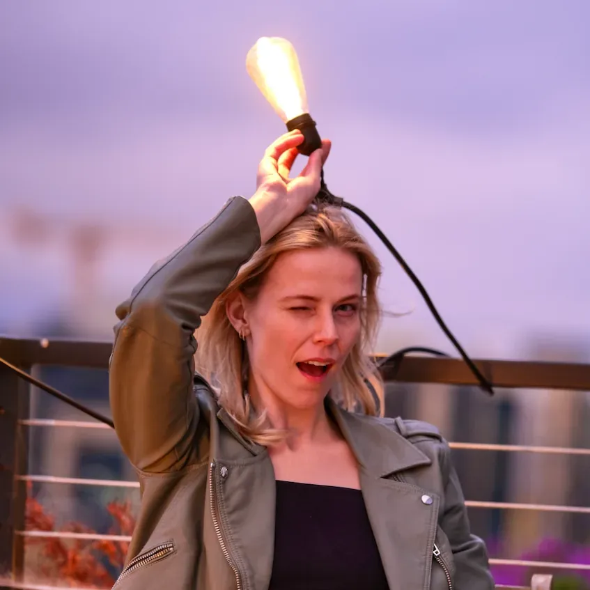 Kayla Cross winking while holding a glowing light bulb over her head.